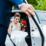 Groom open door of limousine and take hand to bride