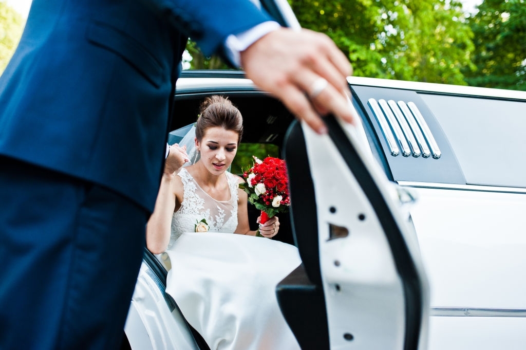 Groom open door of limousine and take hand to bride
